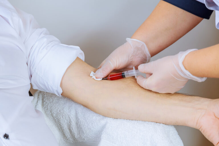 The nurse takes a blood sample, inserting a needle into a man's vein. Laboratory research.
