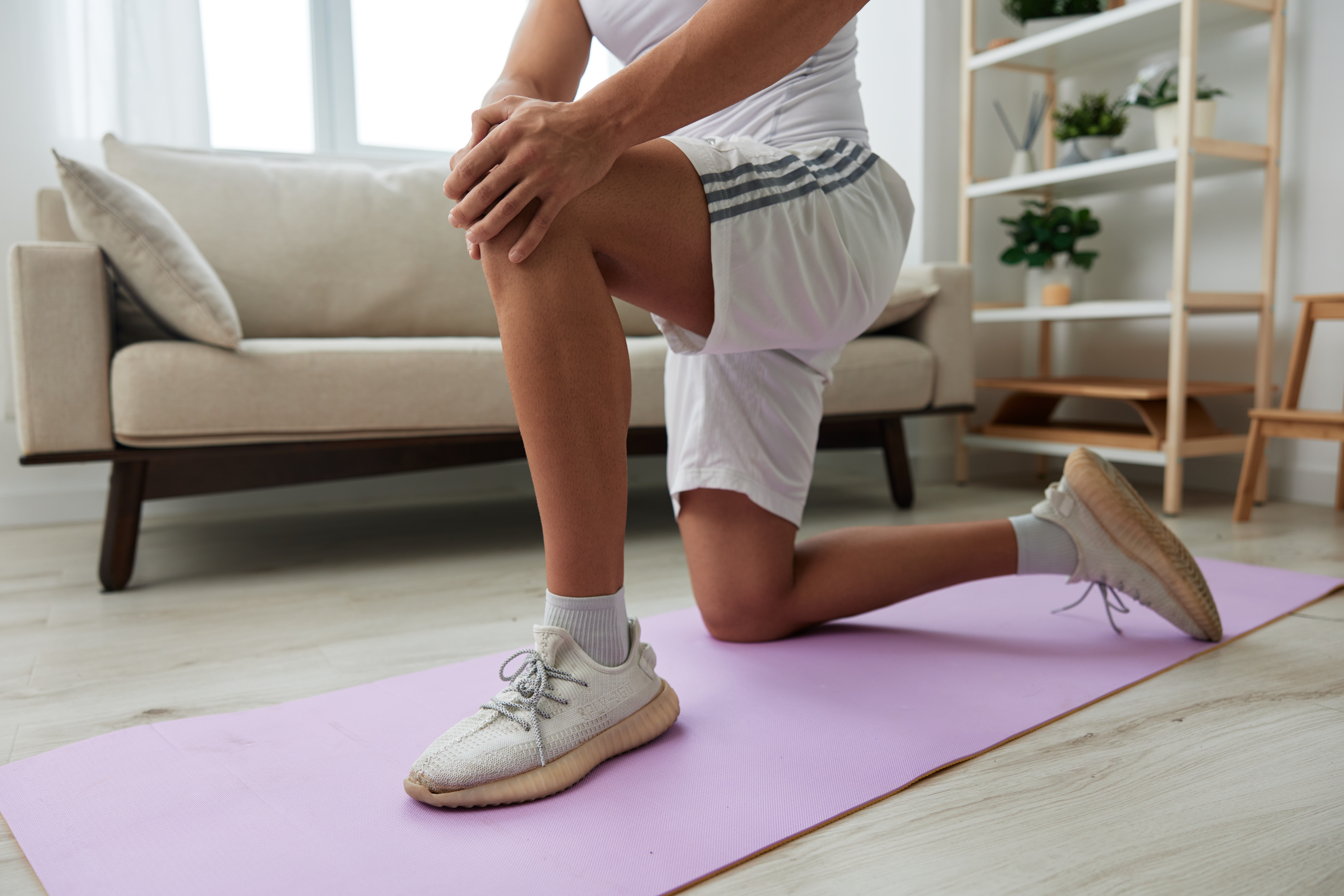 Man sports pain in the side and leg during a workout at home, pumped up man sports, the concept of health without injuries and sprains muscles and ligaments of the body